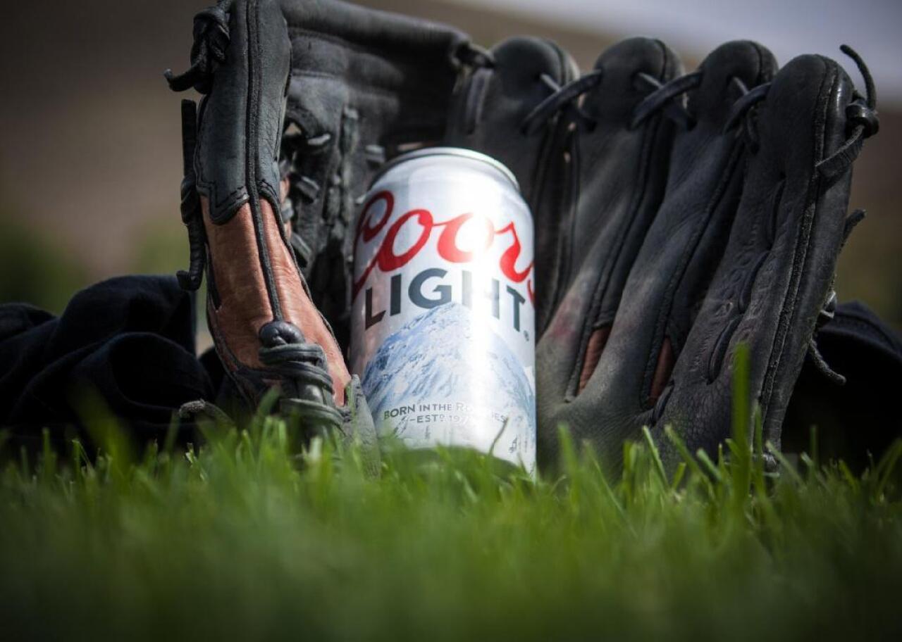 A can of Coors Light sits in a baseball glove. 
