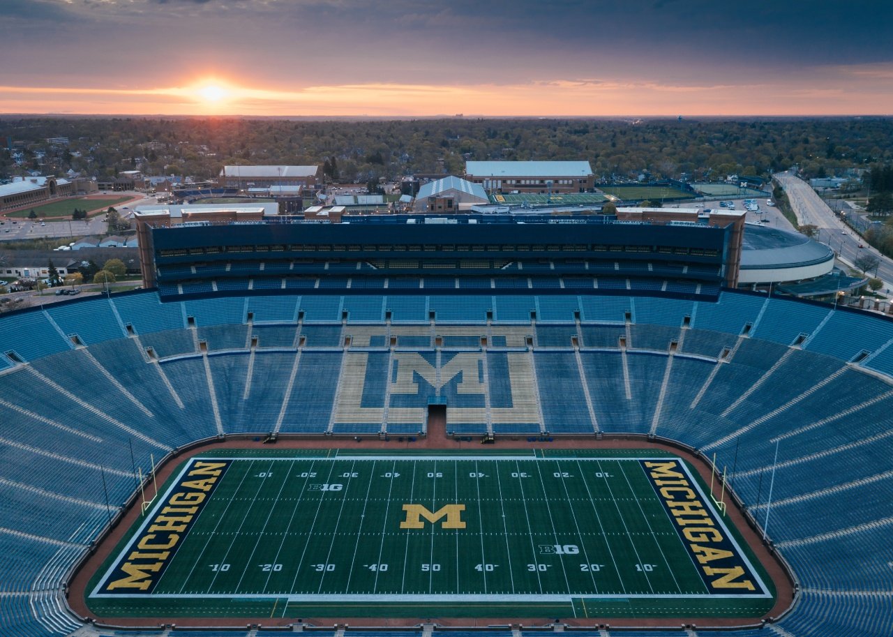 The sun rises behind Michigan Stadium.