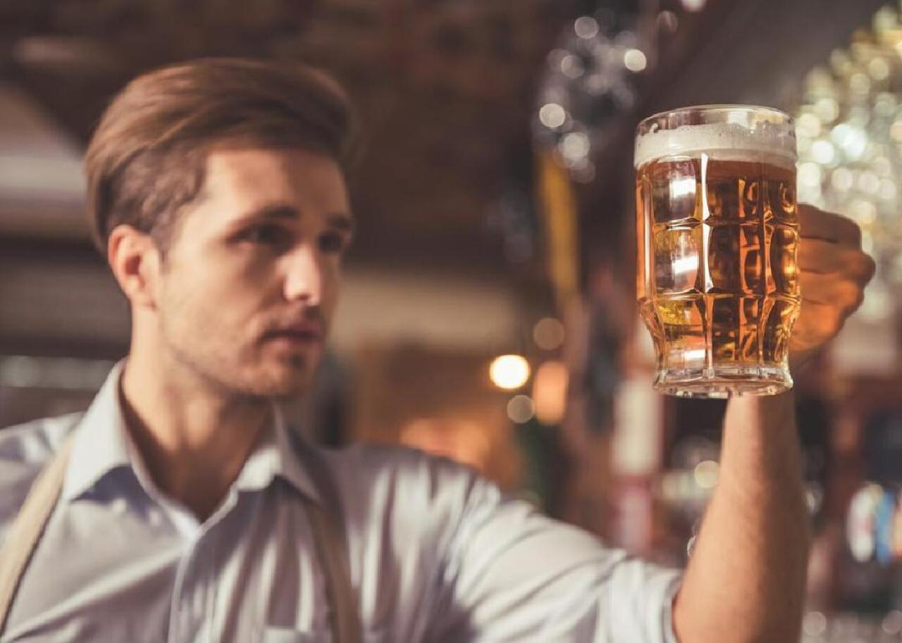 A man holds up a stein filled with beer.