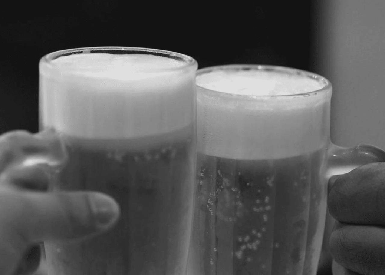 Two mugs of beer with thicky, foamy heads.