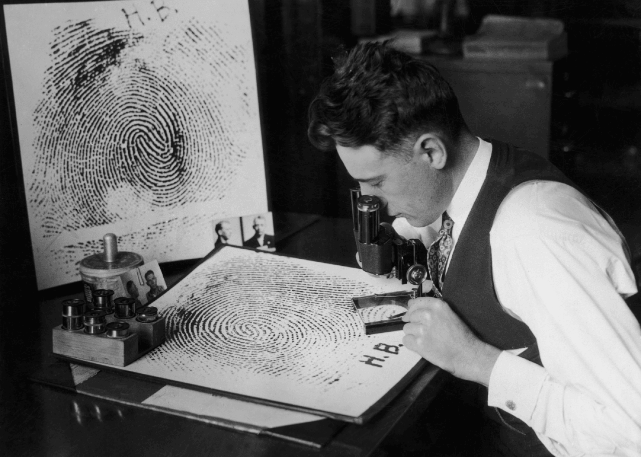 A man examining an enlarged fingerprint circa 1925.