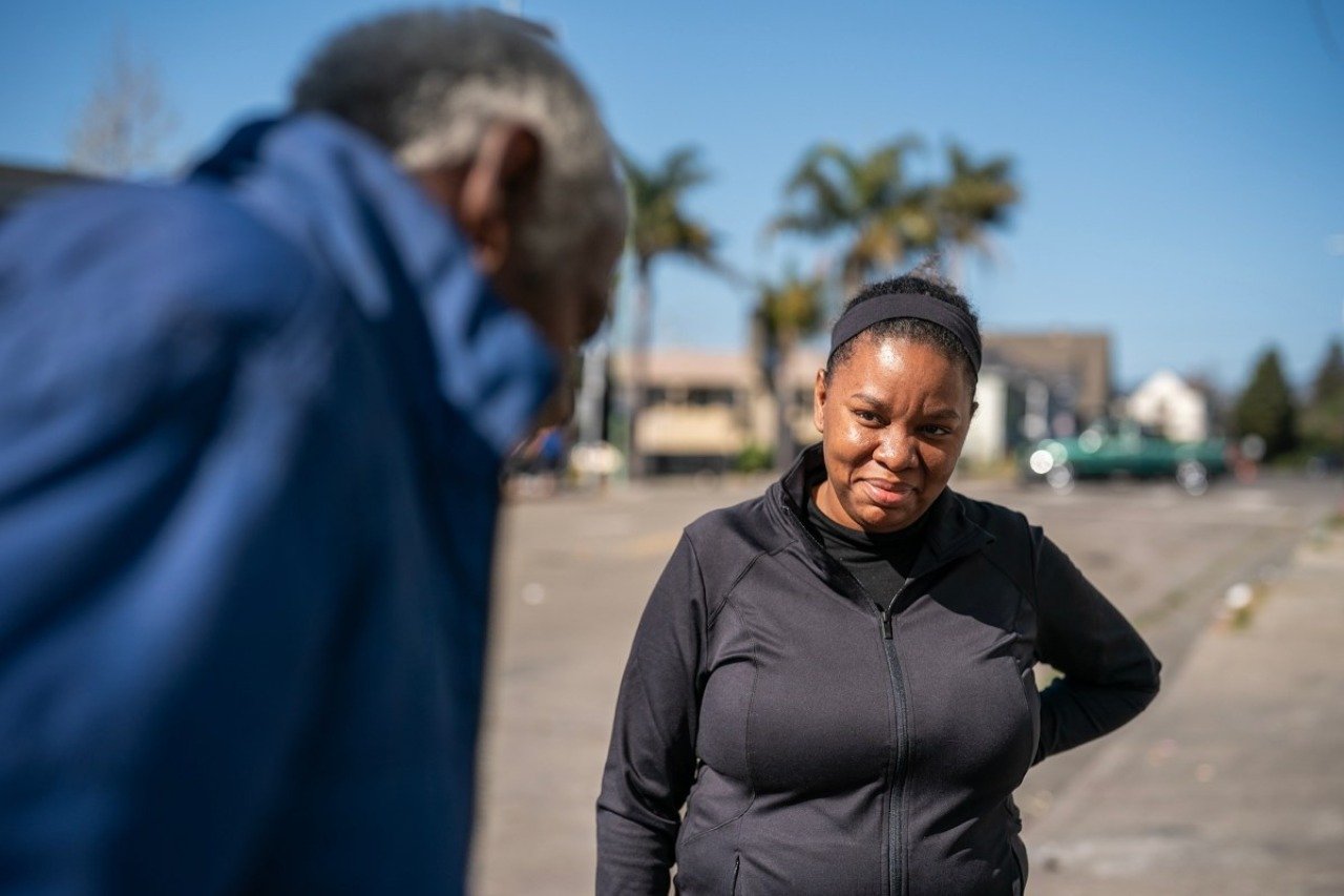 Ashby Dancy with his back toward the camera, speaks with his daughter Ashanti Terrell who is facing the camera and smiling, in Oakland on April 18, 2025. 