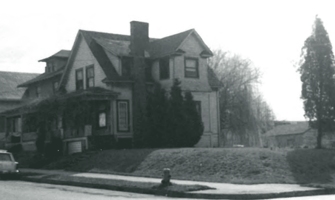 Black-and-white photo of a two-story home with a pointy roof owned by Mike Hepburn’s grandparents. 