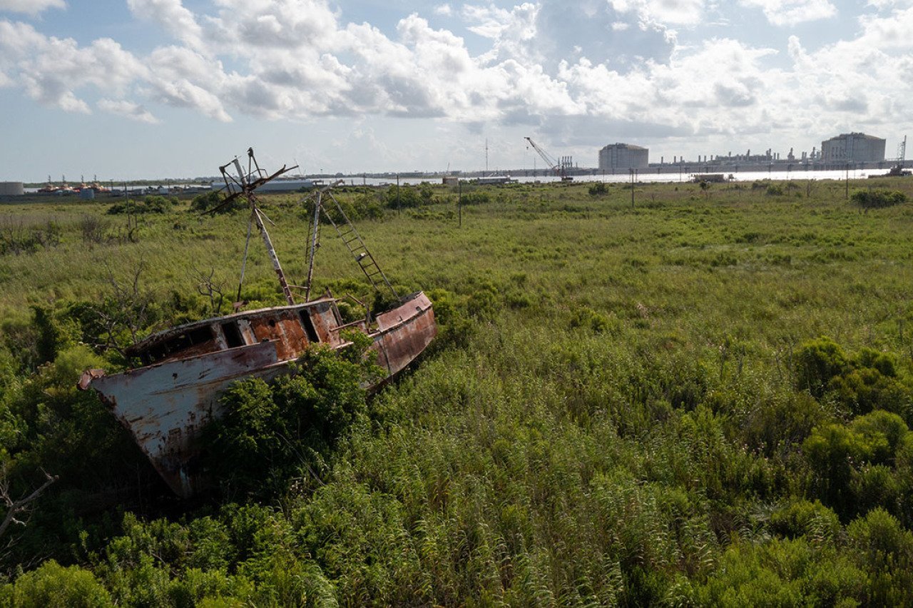 An abandoned fishing boat damaged during Hurricane Laura lies across the river from an expanding liquefied natural gas export terminal in Cameron Parish, LA.
