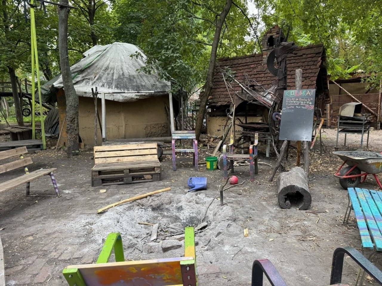 Structures and makeshift furniture on a dirt lot of Adventurous Construction Playground Kolle 37 where children can make or destroy their own buildings.