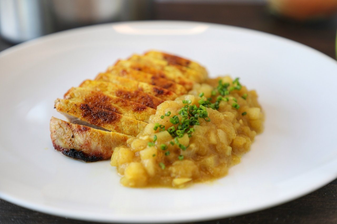 A plate of sliced grilled porkchop with apple chutney.