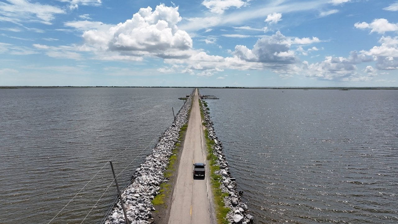 Aerial view of road where Isle de Jean Charles clings to the Louisiana coast by a narrow road flanked on both sides by rising gulf waters.