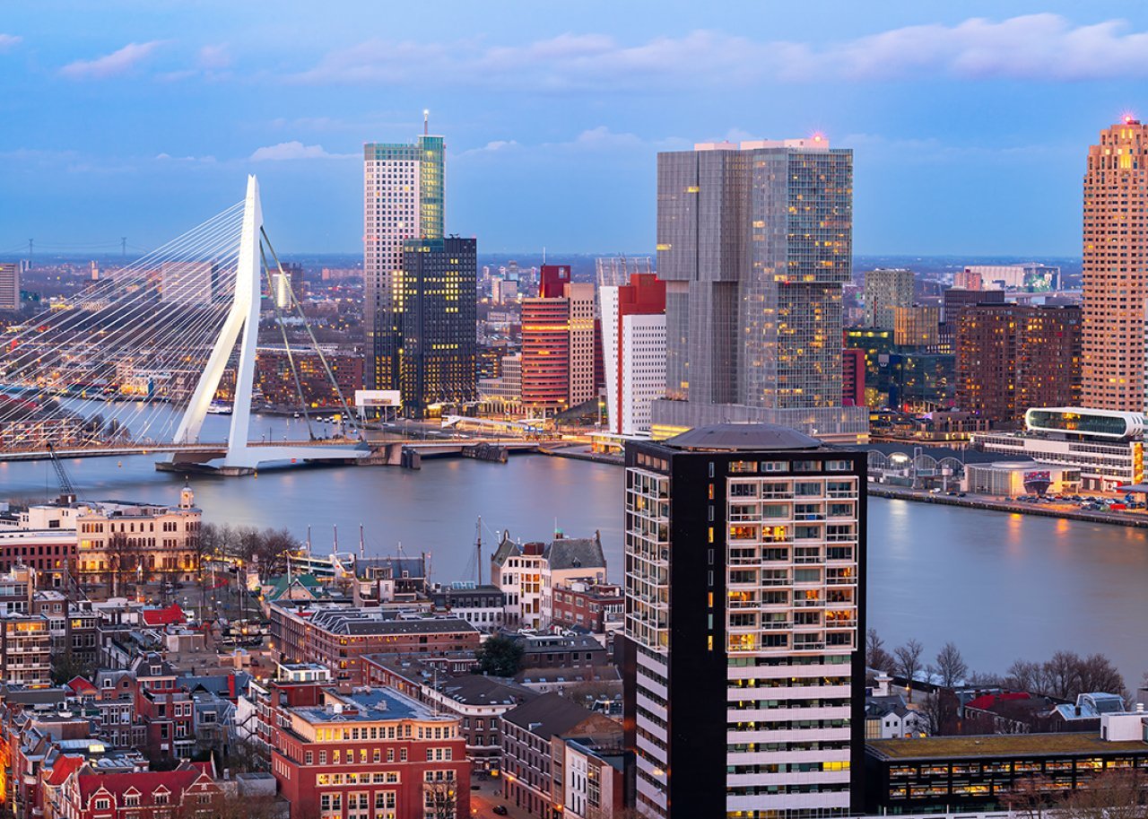 View of the Rotterdam city skyline over the Nieuwe Maas River during twilight in Netherlands.
