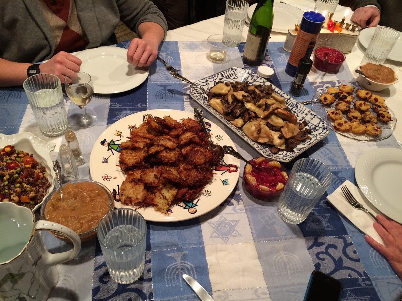 Fried foods on a table with a blue and white tablecloth at a Hannukah Party.