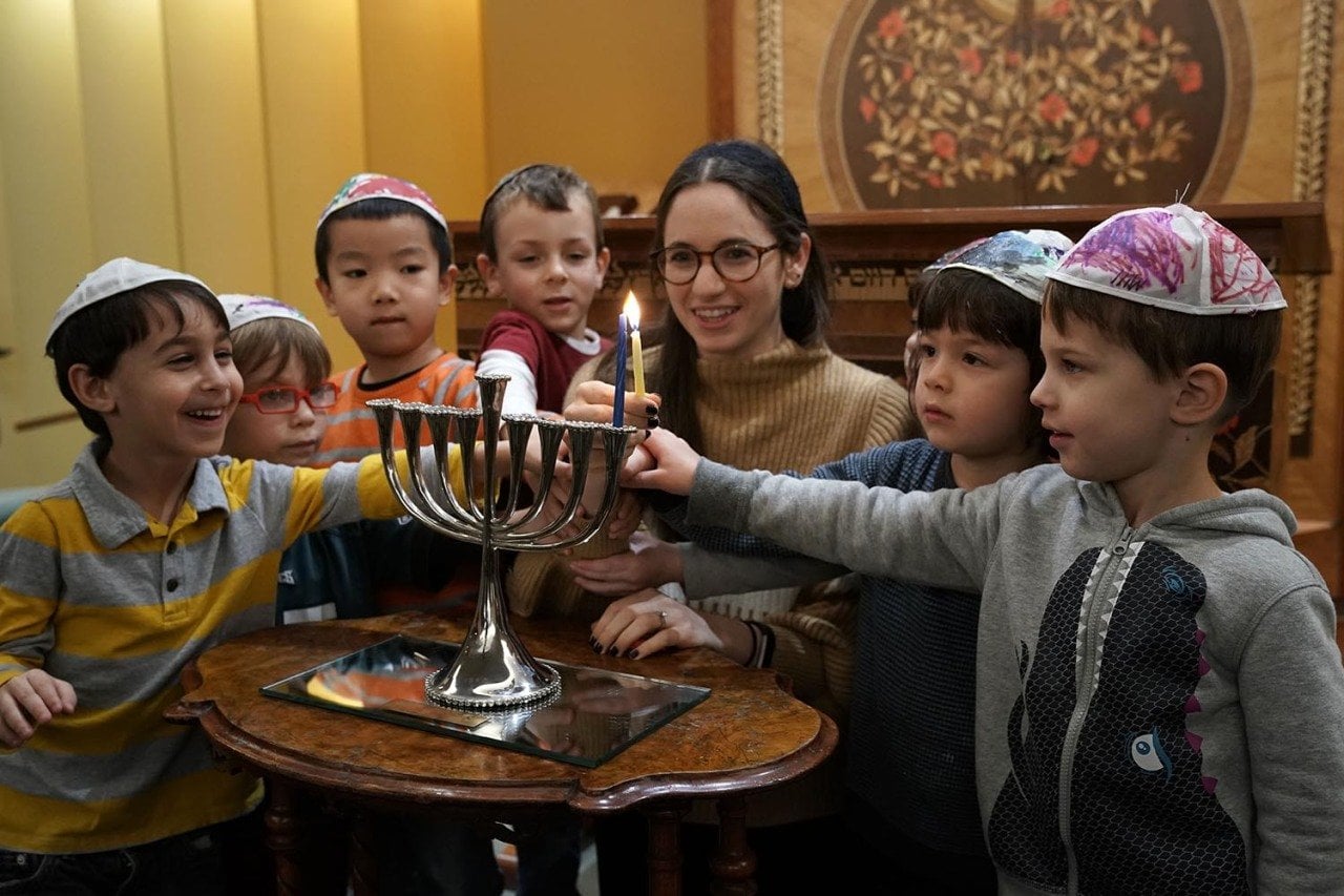A small group of pre-schoolers from Gan HaYeled learn how to light a Hanukkah menorah from Rabbi Sarah Krinsky at Adas Israel Congregation.
