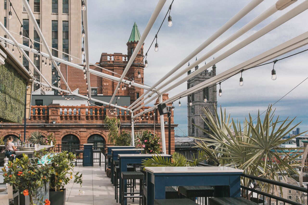 View from the patio of Hotel Place d’Armes with fairy lights hung on a trellis and a view of the city in the background.