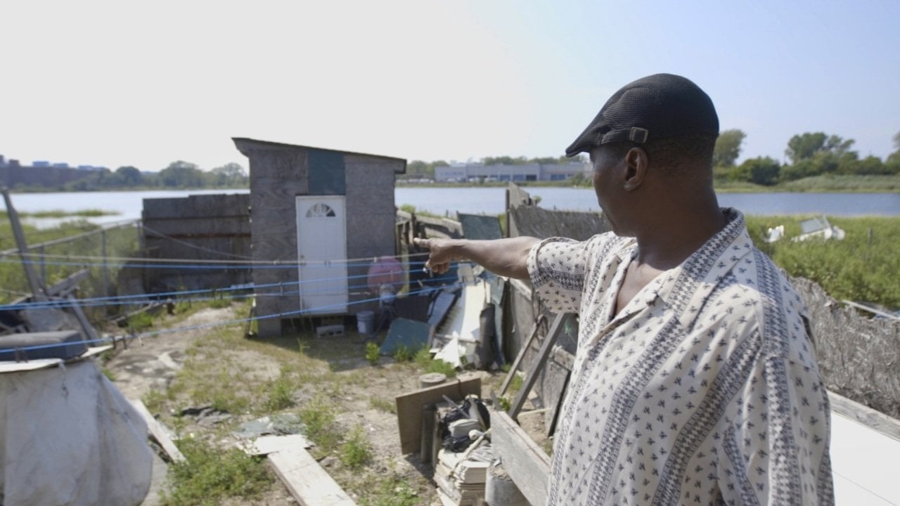 Baba Ndanani, resident of one of New York's most flood-prone neighborhoods, pointing out a spot that concerns him in his backyard.