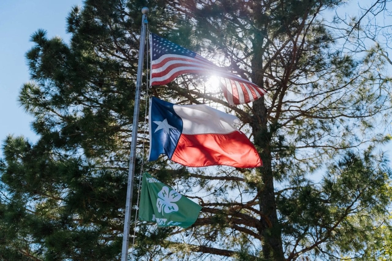 The American and Texas flags fly in Kinney County, Texas. A new Texas state law requires nearly every county sheriff to participate in the Section 287(g) program.