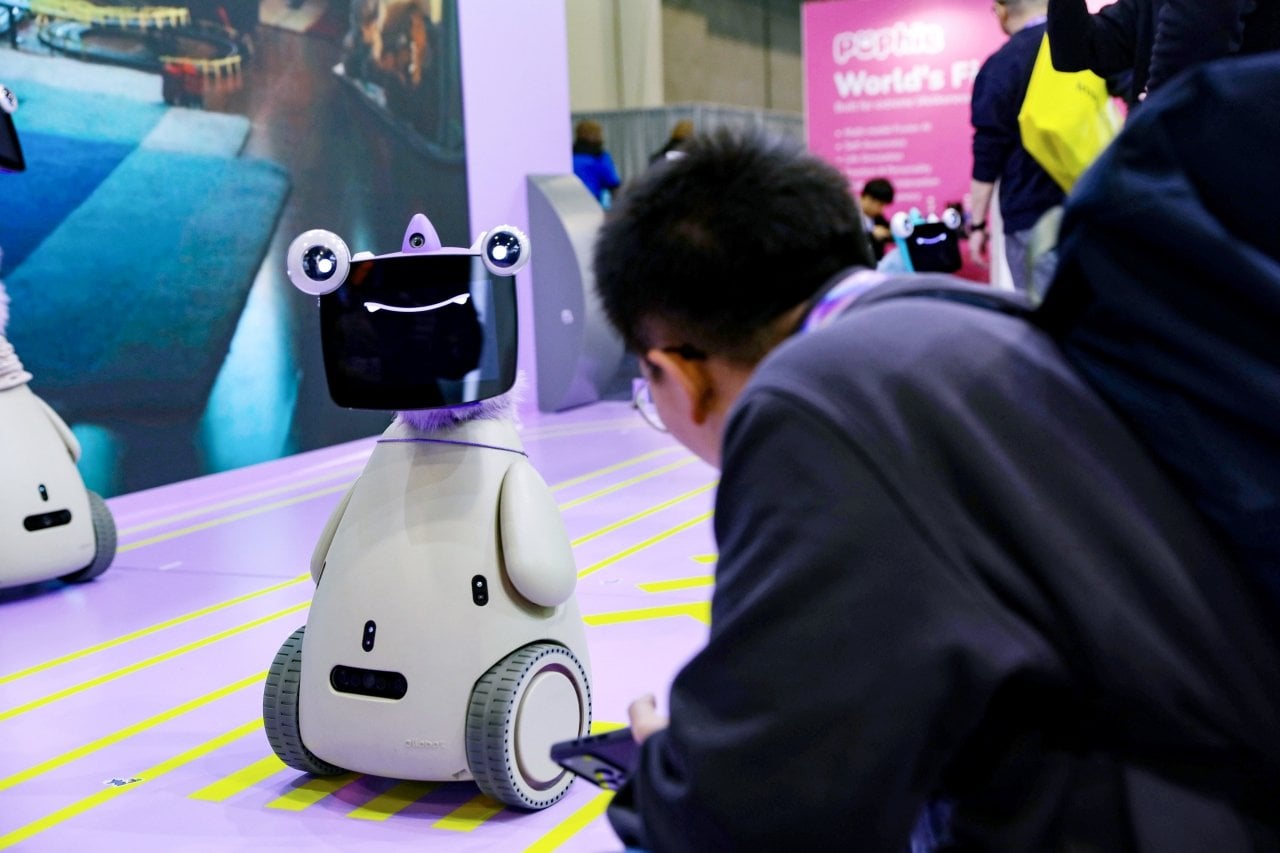 A spectator looks a robot pet which has wheels to move around and a tablet on its 