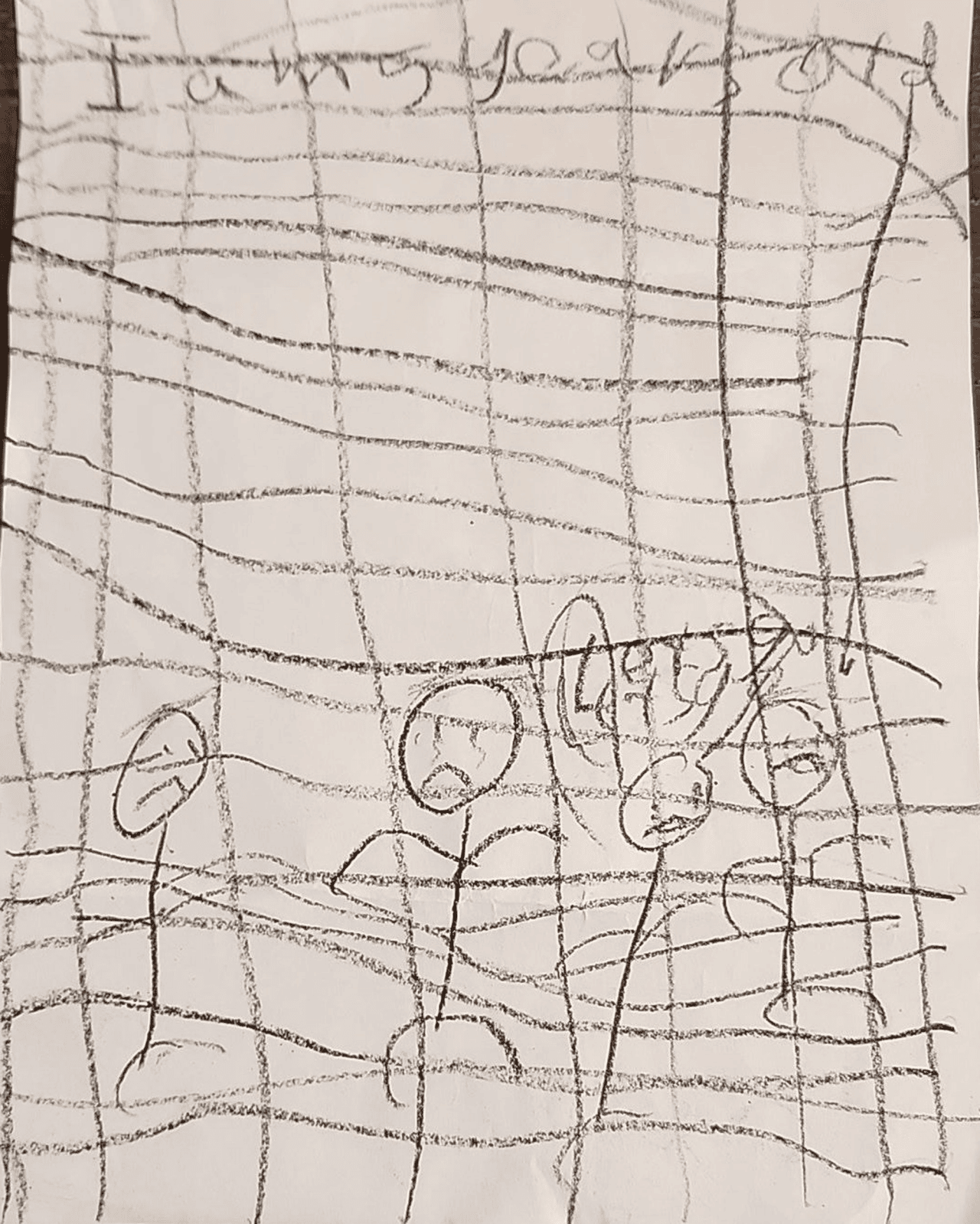 A photo of a child&rsquo;s stick figure drawing showing four people behind bars. The words &ldquo;I am 5 years old&rdquo; are at the top of the page. Lower down, next to the figures, are the words &ldquo;let us go.&rdquo;