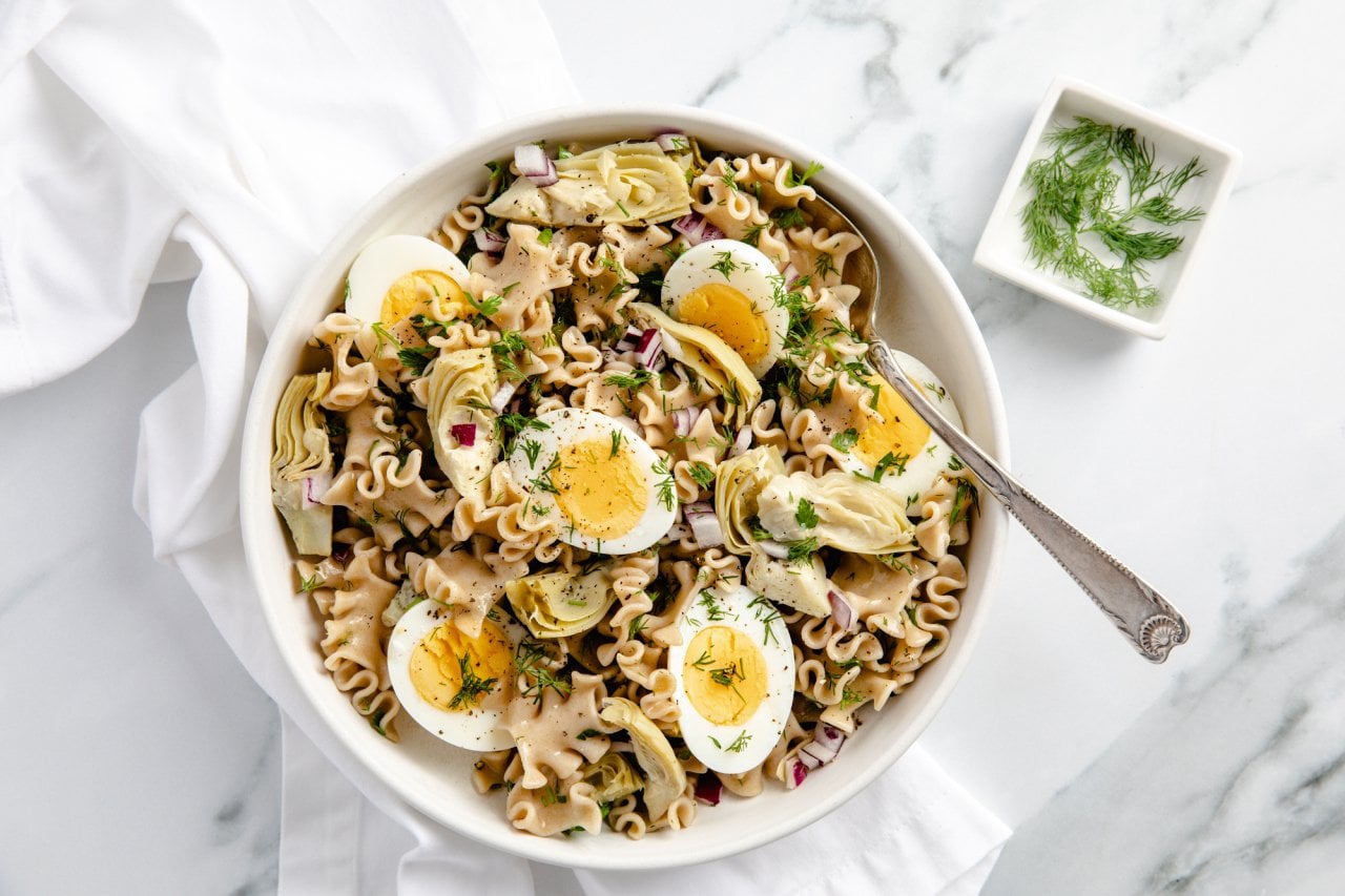 Top-down view of bowl of egg pasta salad using lasagna noodles, garnished with dill.