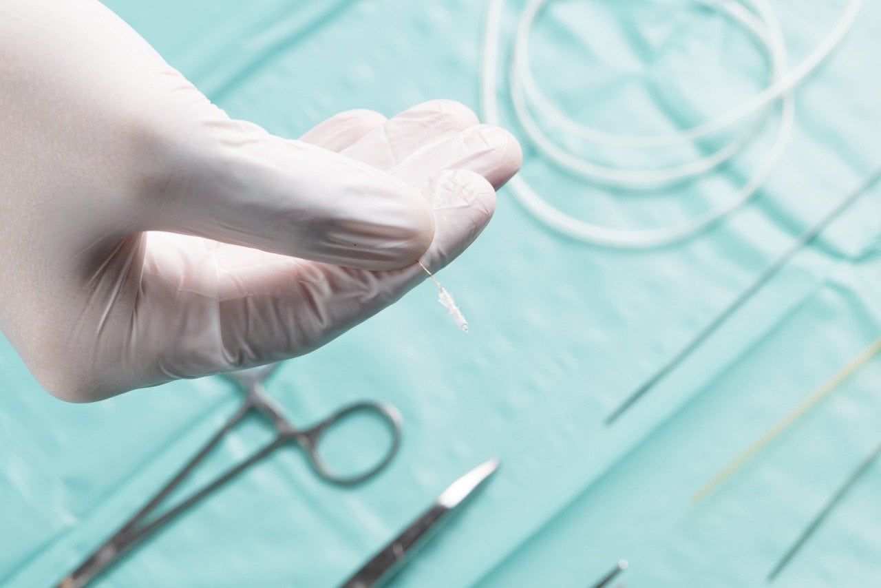 A gloved hand holding a microrobot of 1.8 millimeters in diameter that can move through brain tissue along curved, pre-planned 3D paths instead of the straight lines imposed by today&rsquo;s rigid needles. A thin tether provides power, enables tracking and allows retrieval with actions directed by a surgeon with AI providing guidance. 