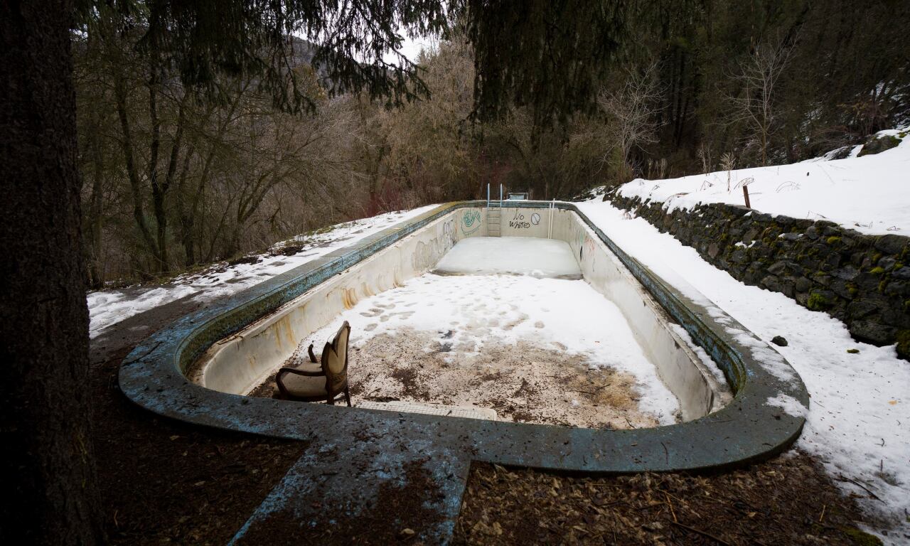 The empty outdoor swimming pool contains a broken chair and a snow-covered bottom at the Logan Canyon property that was once St. Ann's Retreat.