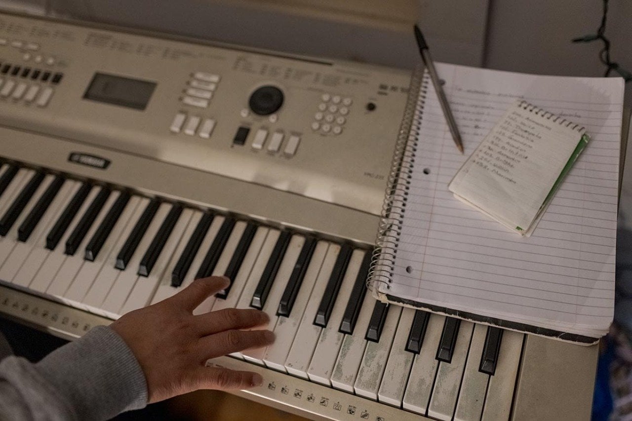 View of one hand on a white keyboard next to where a notepad and notebook sit.