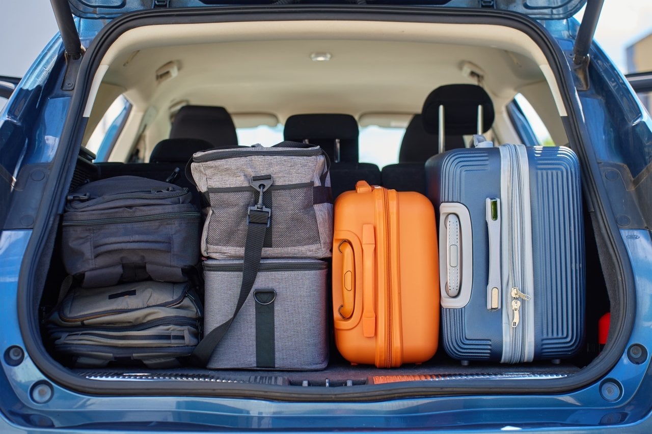 A car trunk packed with backpacks, bags, and suitcases before a road trip.