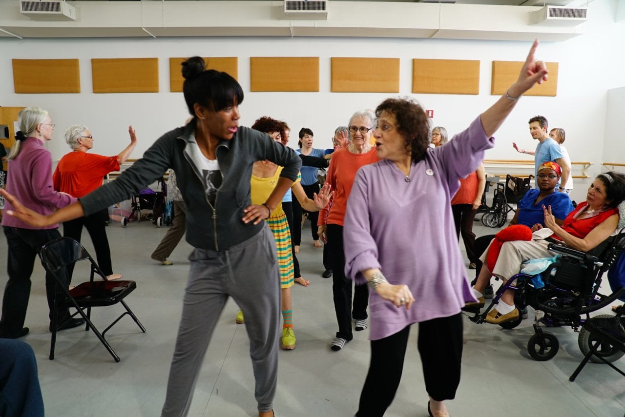 People lined up two-by-two dancing as they walk toward the camera.
