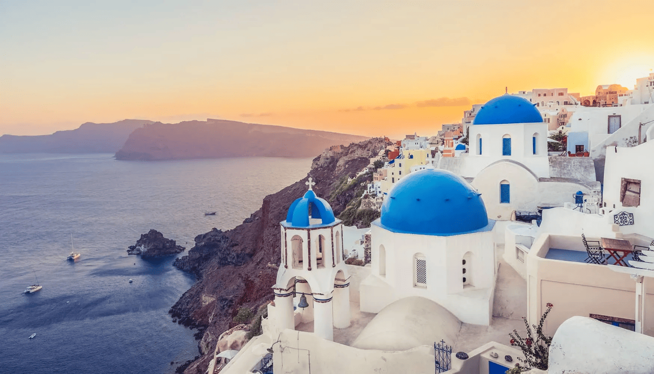 A sunset view of the iconic whitewashed buildings and the open sea in Santorini, Greece.