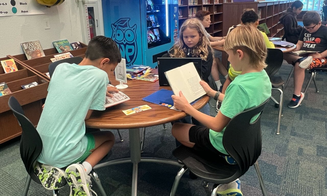 Third grade students Brady Jackson, Everly Collier and Finn Fratila read books in the Windsor Park Elementary library.