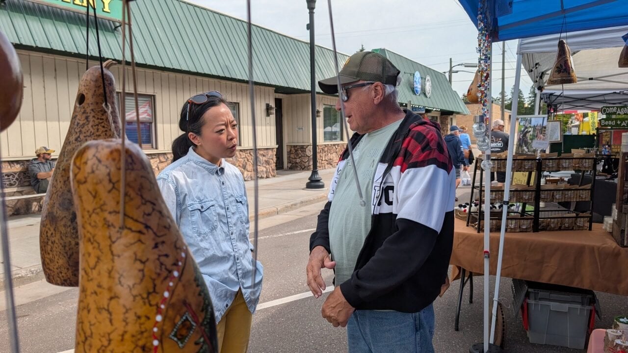 Hong speaks to Bob Boesch next to the thunder gourds they sell.