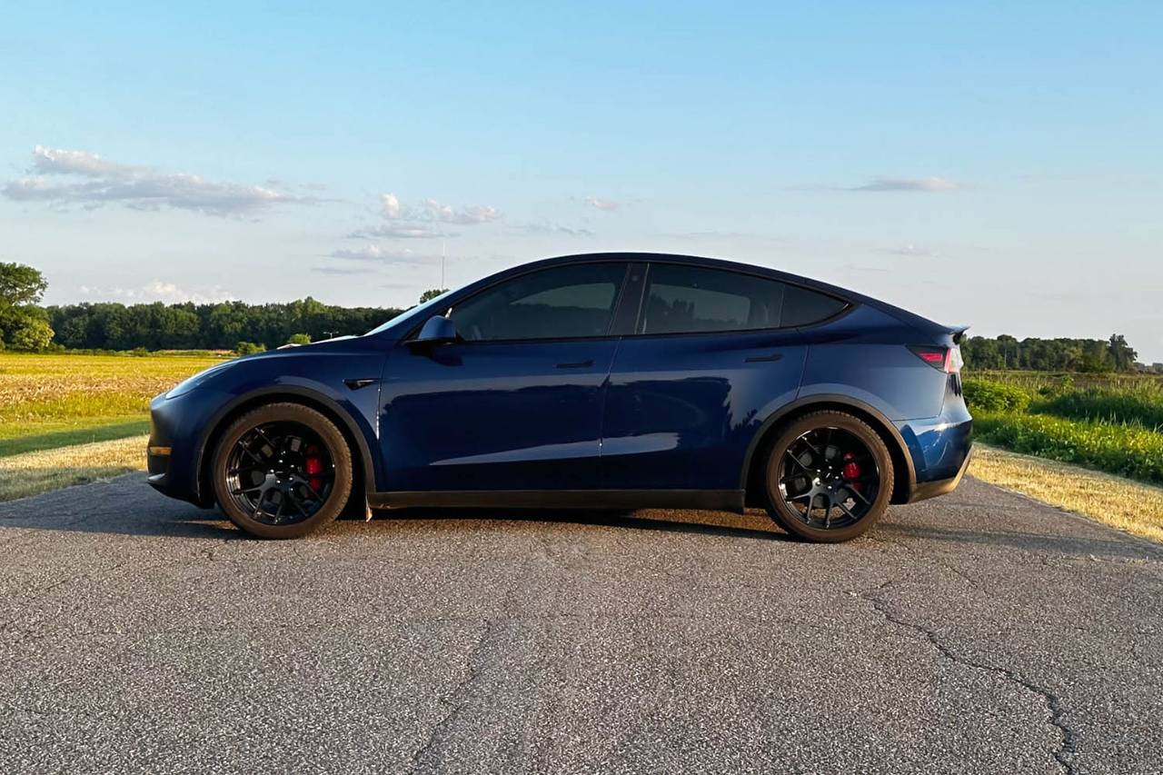 2023 Tesla Model Y side view parked on road.