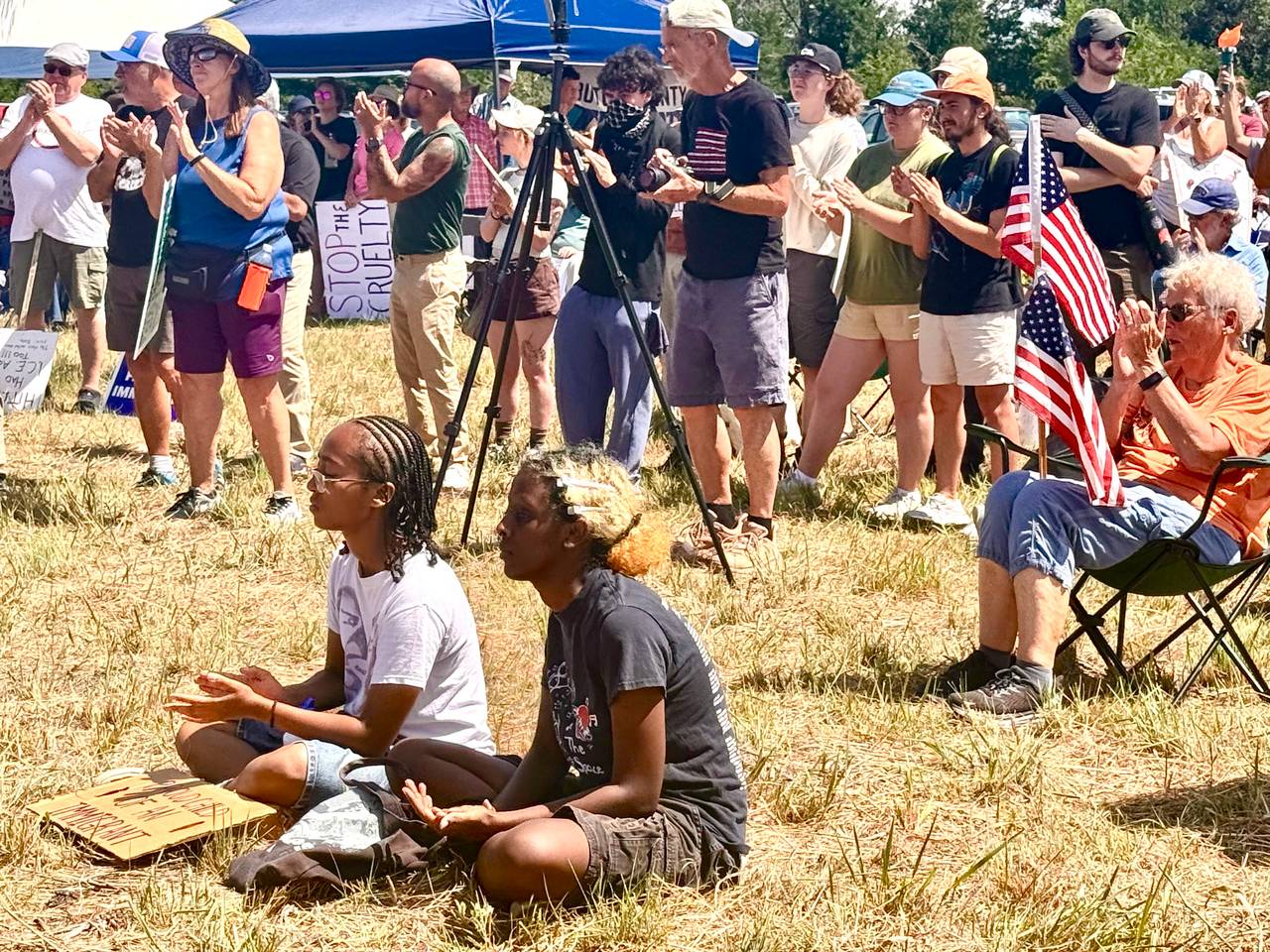 Rallygoers listen to speakers at a private lot within eyeshot an ICE detention facility for migrants established last year in McCook.