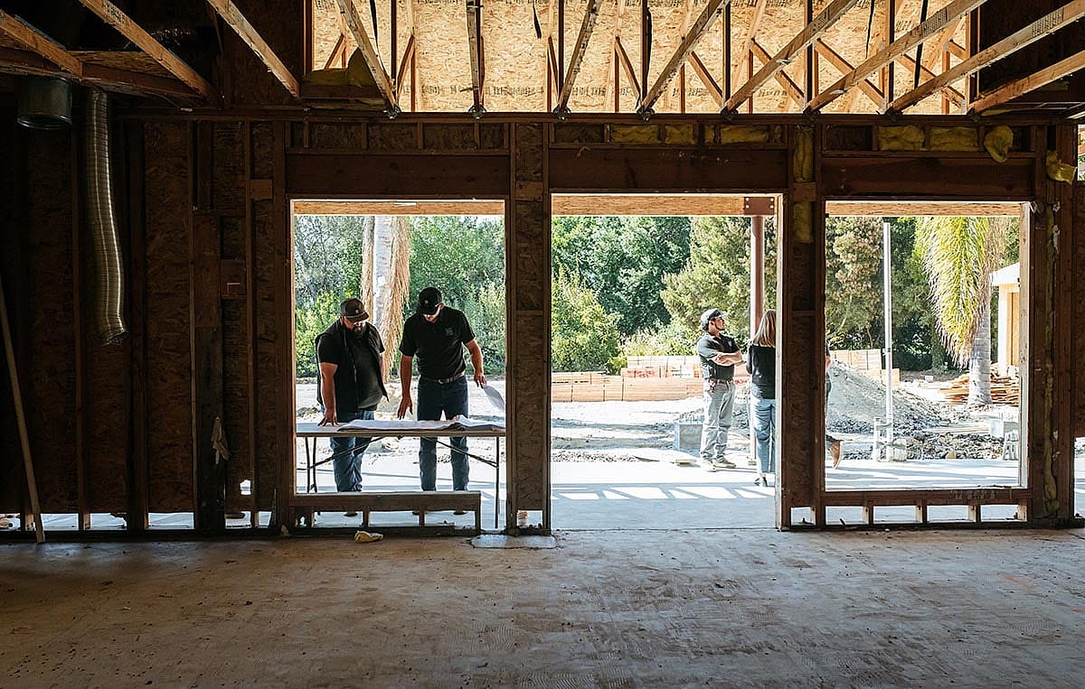 Builder-contractors reviewing blueprint plans during a remodeling of a building project.