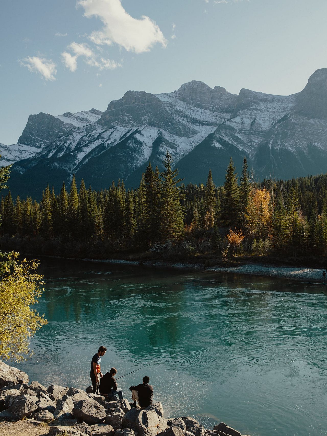 A portrait view of a group of friends fishing by a rive in the Canadian Rockies in Canmore.