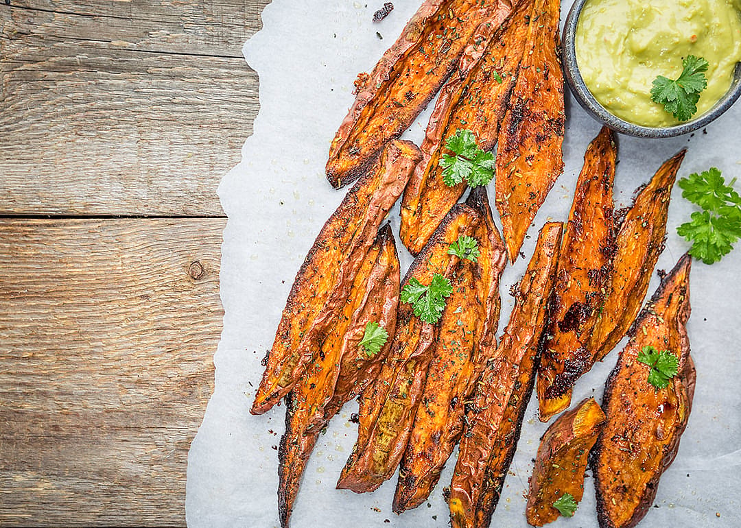 Seasoned roasted or air-fried sweet potato wedges served with a green dipping sauce,