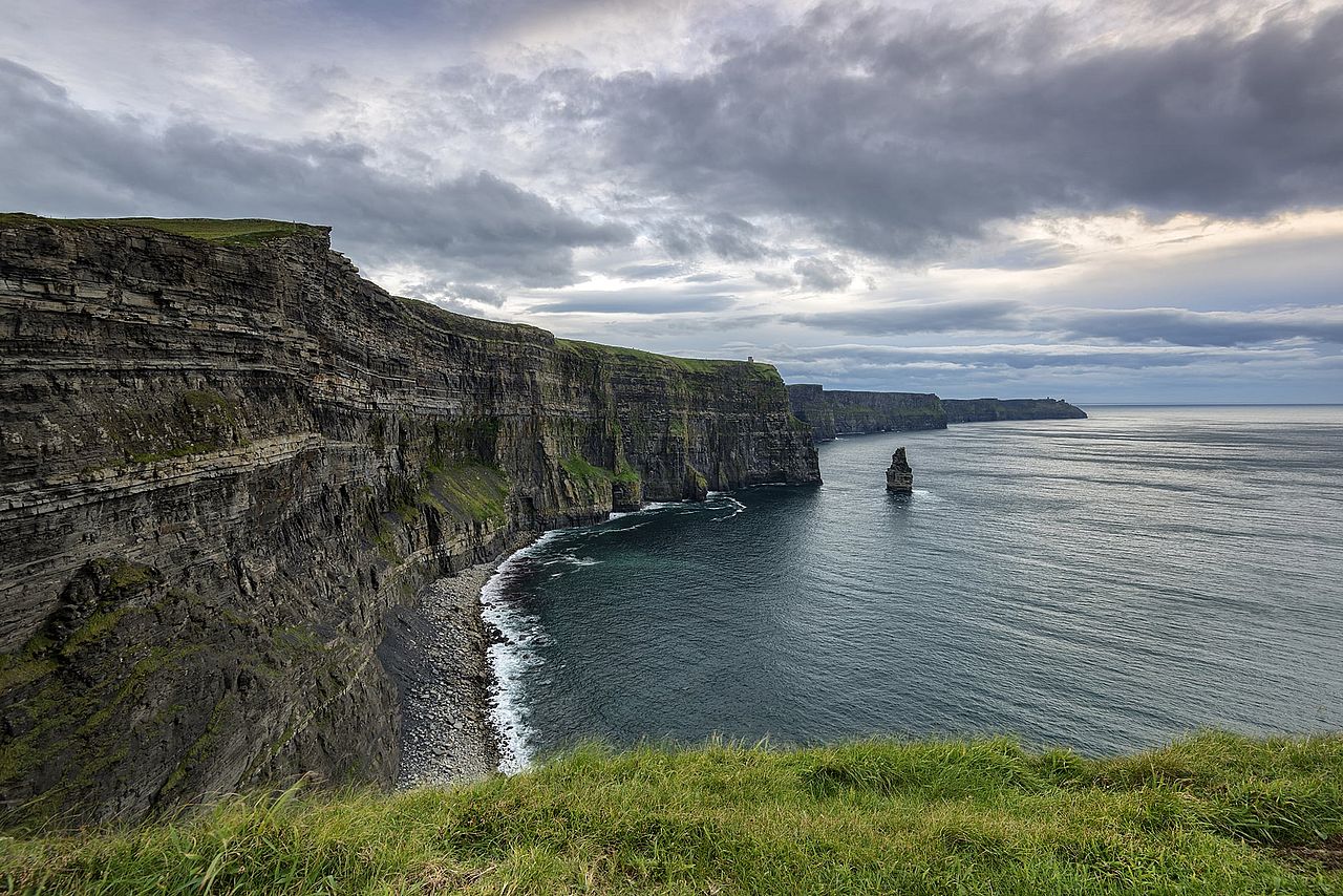 The rock faces and green turf of the Cliffs of Moher overlooking the Atlantic Ocean in County Clare, Ireland