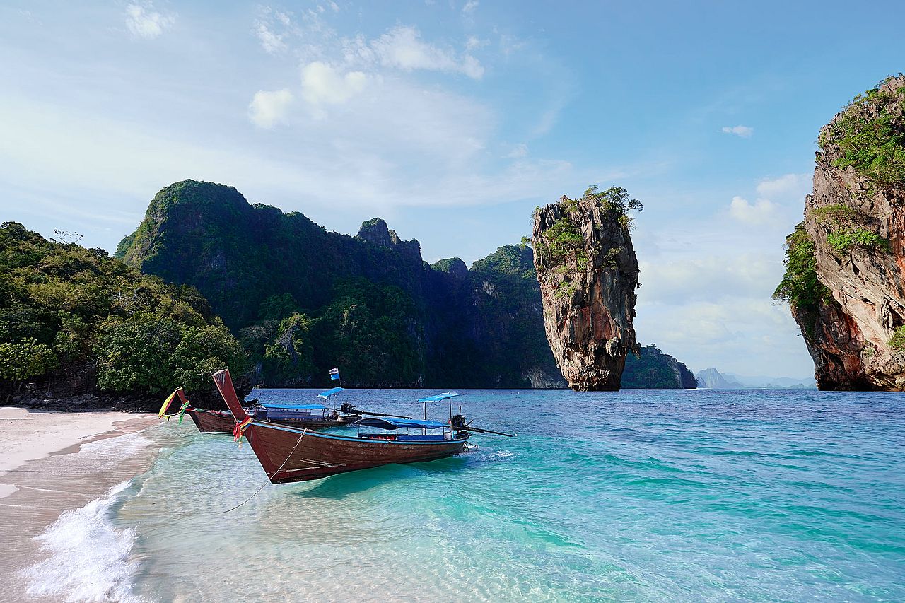 Beautiful landscape with traditional longtail boats, rocks, cliffs, tropical white sand beach in Thailand.
