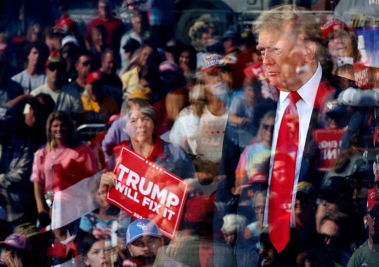 President Donald Trump is seen through protective bullet-resistant glass where his supporters are reflected during a campaign rally at Gastonia Municipal Airport on November 02, 2024 in Gastonia, North Carolina.