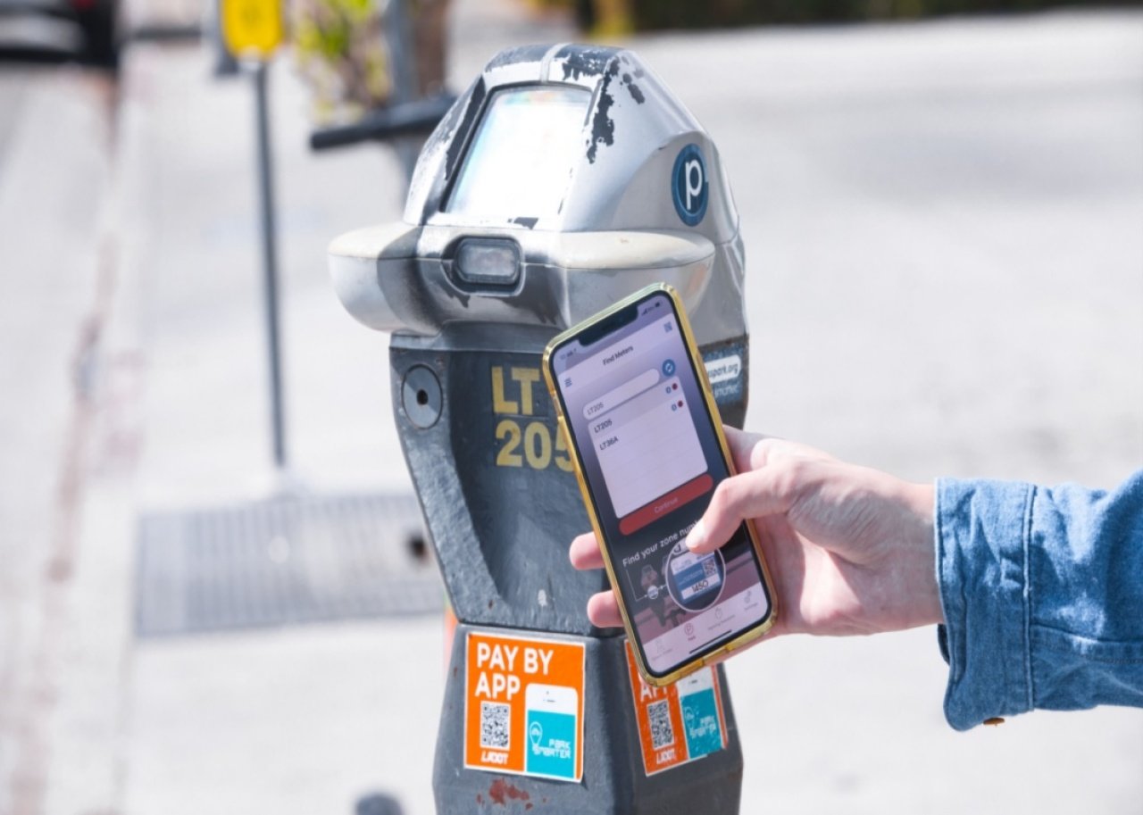 A person uses their smartphone to scan a QR code on a parking meter.