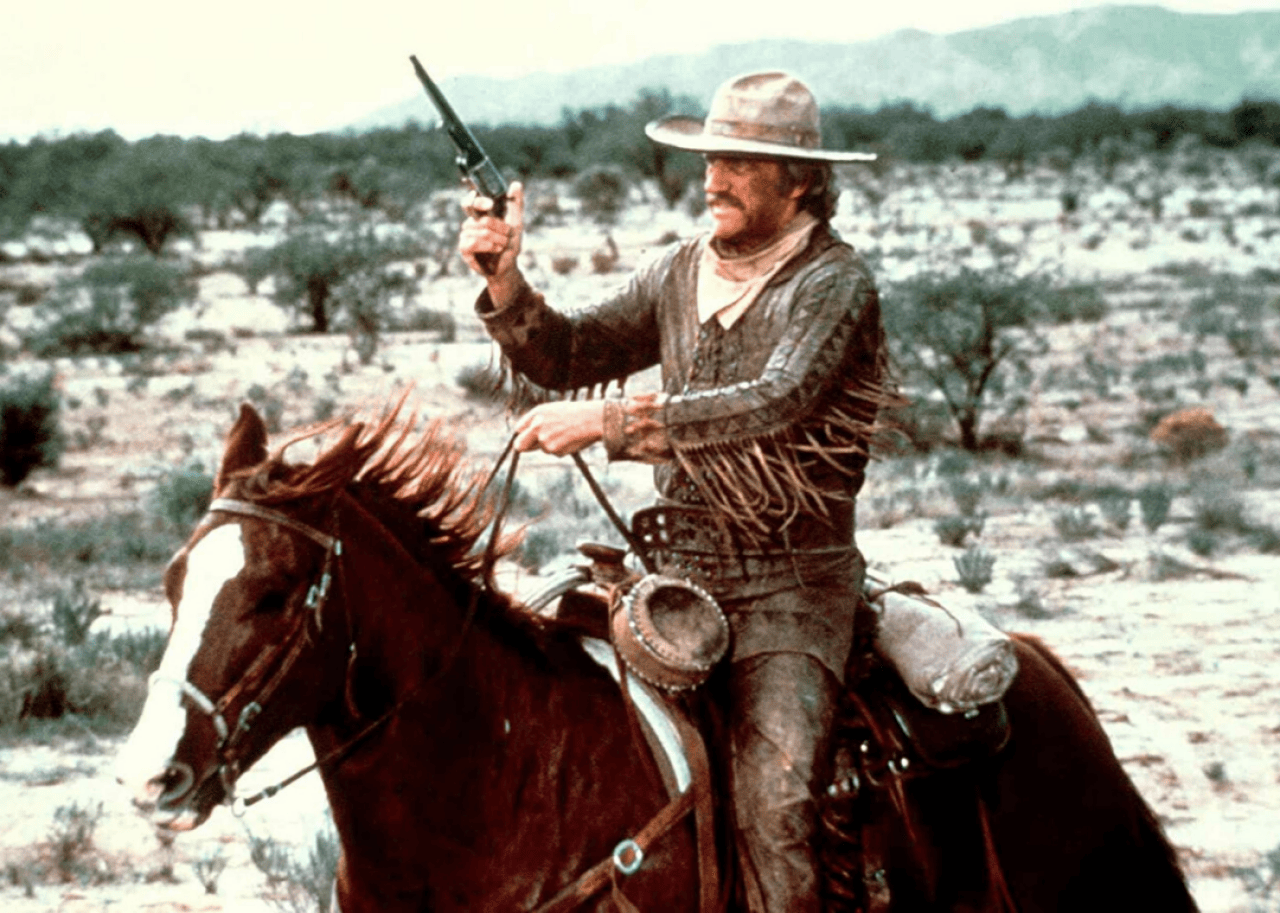 A man holding a pistol up on a galloping horse.
