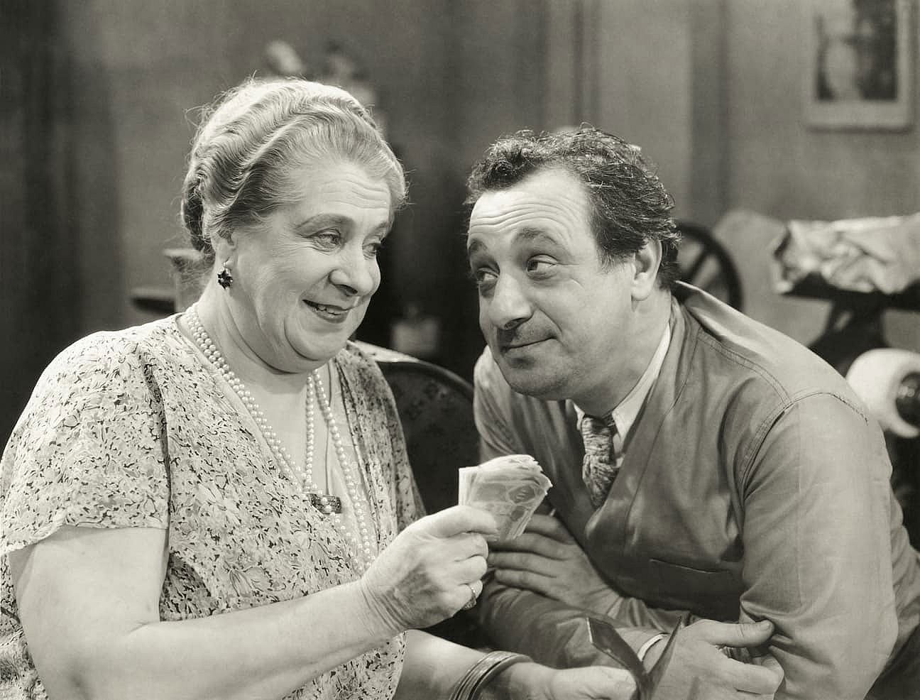 Black and white vintage photo of a man and a woman looking at each other while she holds some money