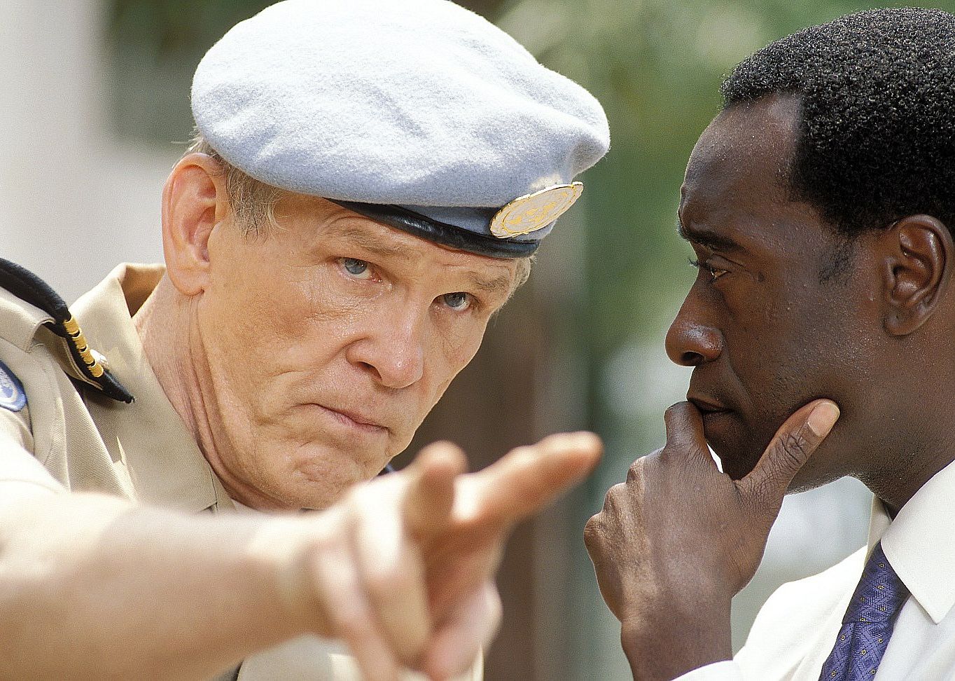 Nick Nolte in a military uniform pointing at something as he speaks to Don Cheadle.