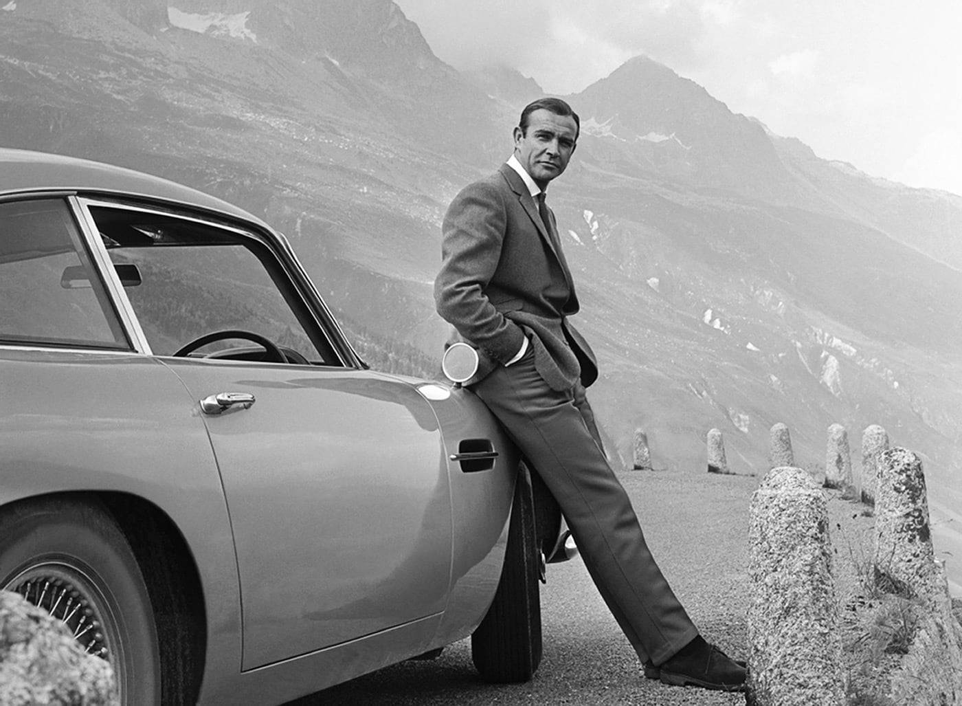 Actor Sean Connery poses as James Bond next to his Aston Martin DB5 during the filming of 'Goldfinger', Switzerland, 1964.