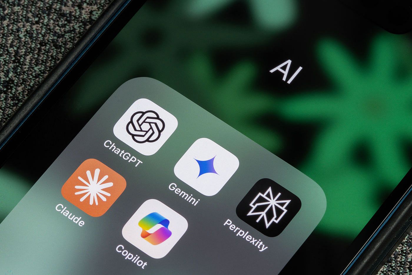 ChatGPT, Gemini, Microsoft Copilot, Claude, and Perplexity app icons are seen on the screen of an iPhone.