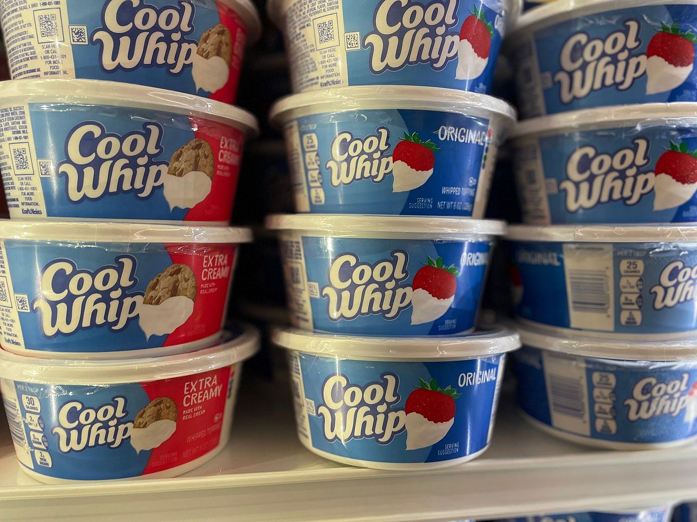 Containers of Cool Whip in a grocery store frozen foods section.