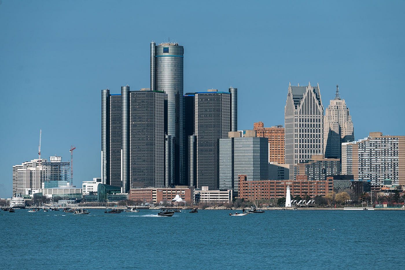 View of the Detroit skyline from across the Detroit River, featuring the Renaissance Center and surrounding high-rise buildings on a clear spring day.