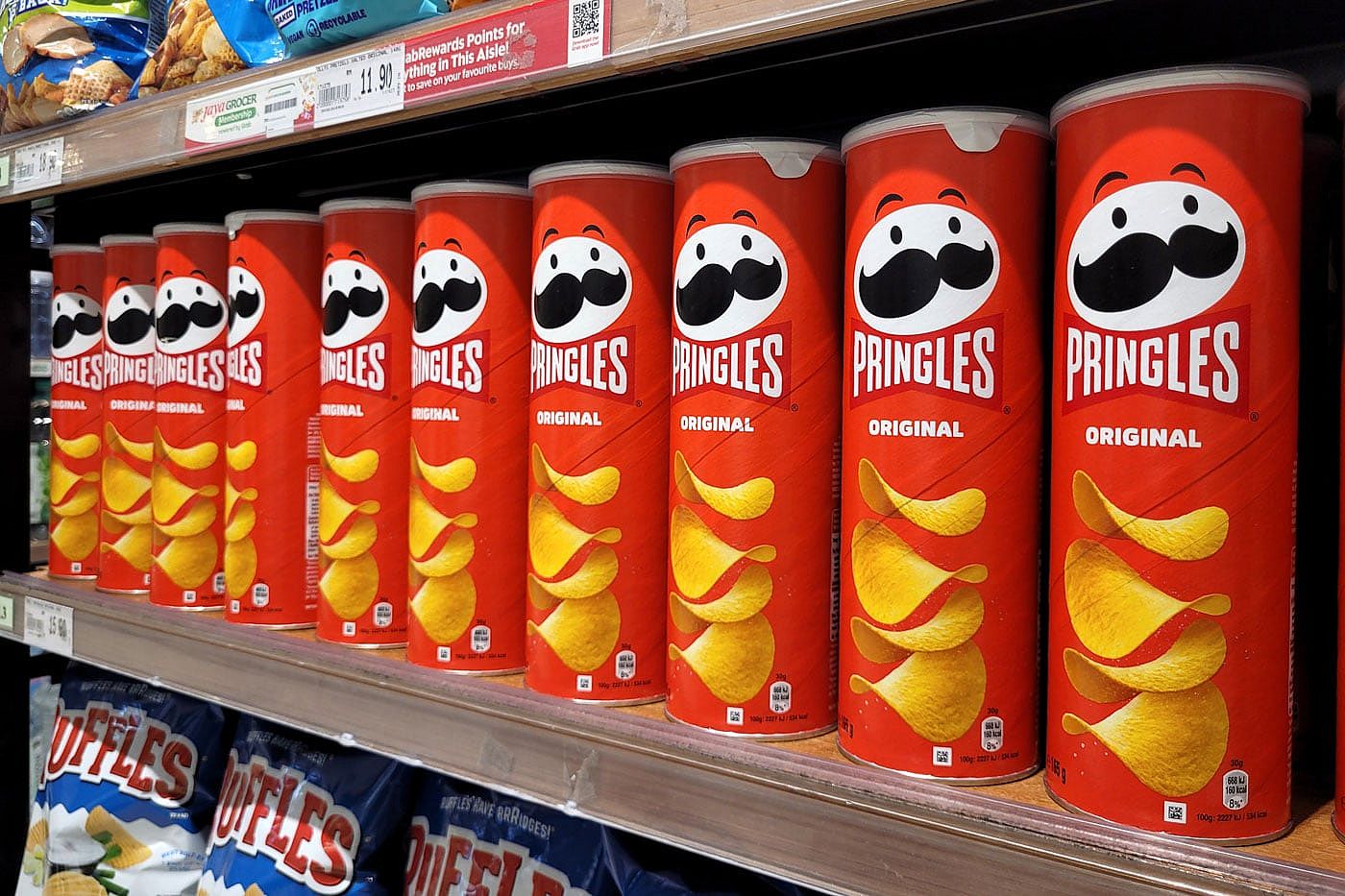 Cans of original flavor Pringles sitting on a grocery store shelf.