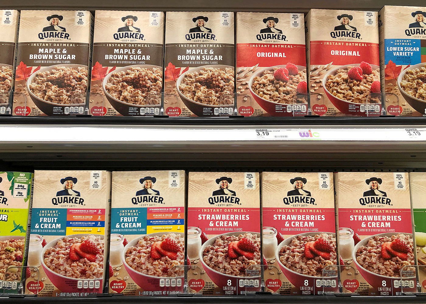 Grocery shelf displaying various flavors of Quaker Instant Oatmeal.