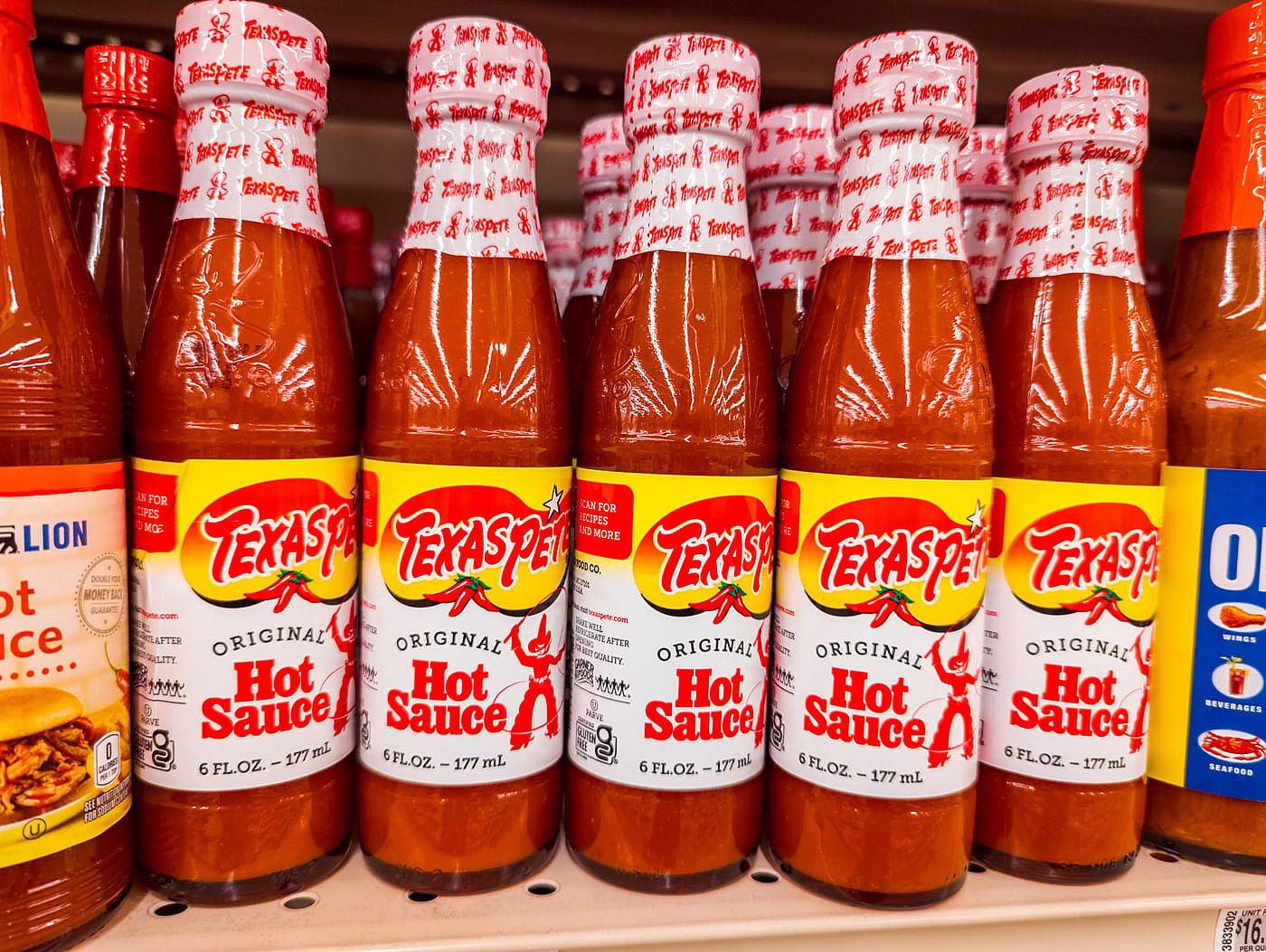 Bottles of Texas Pete hot sauce sitting on a grocery store shelf.