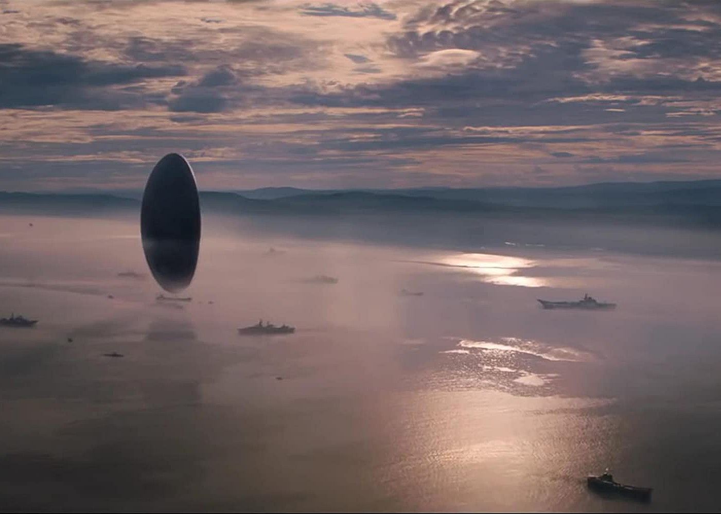 A large round craft hovering over a foggy body of water.