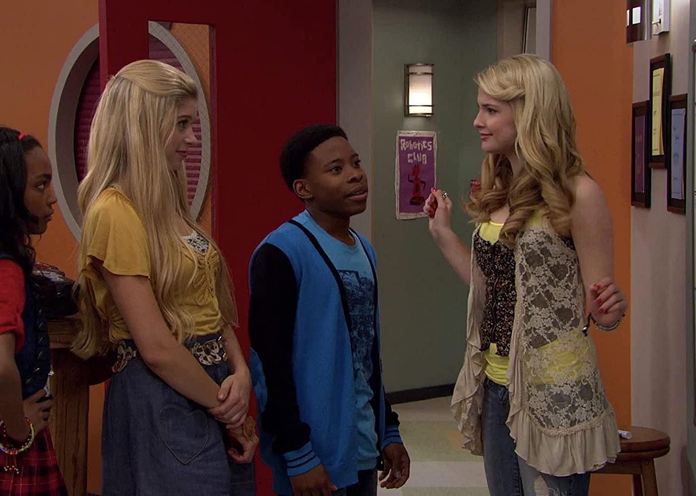 Four kids stand in a hallway talking.