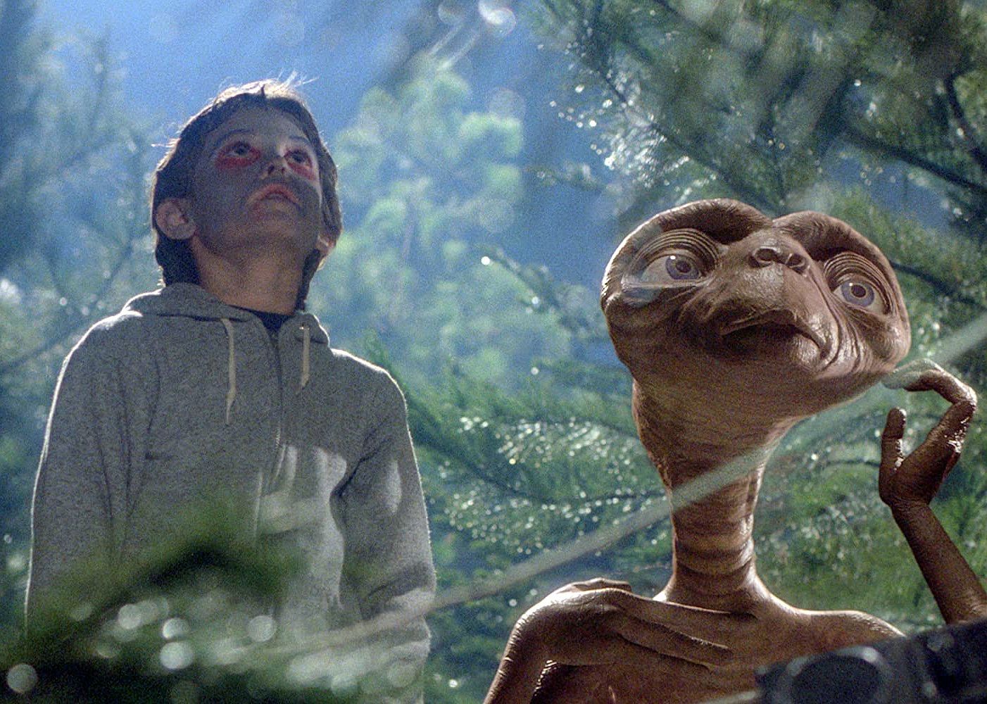 A little boy and an alien looking up at the sky together.